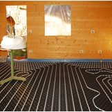A hydronic closed loop underfloor heating system laid out on molded insulated panel in EPS with a spooling table inside a partially constructed wooden house